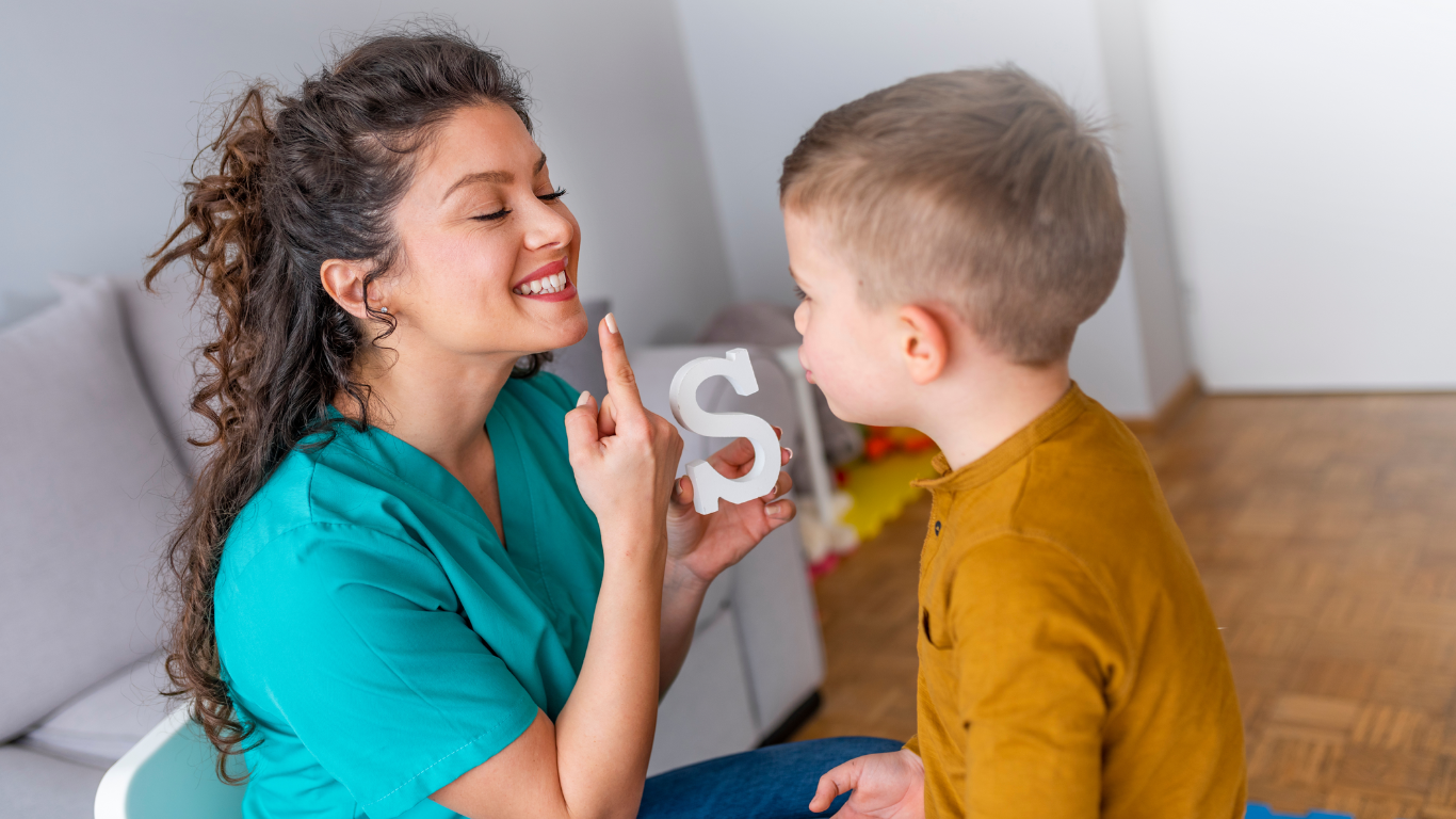 Speech Therapist training the child to speak say the letter 'S'